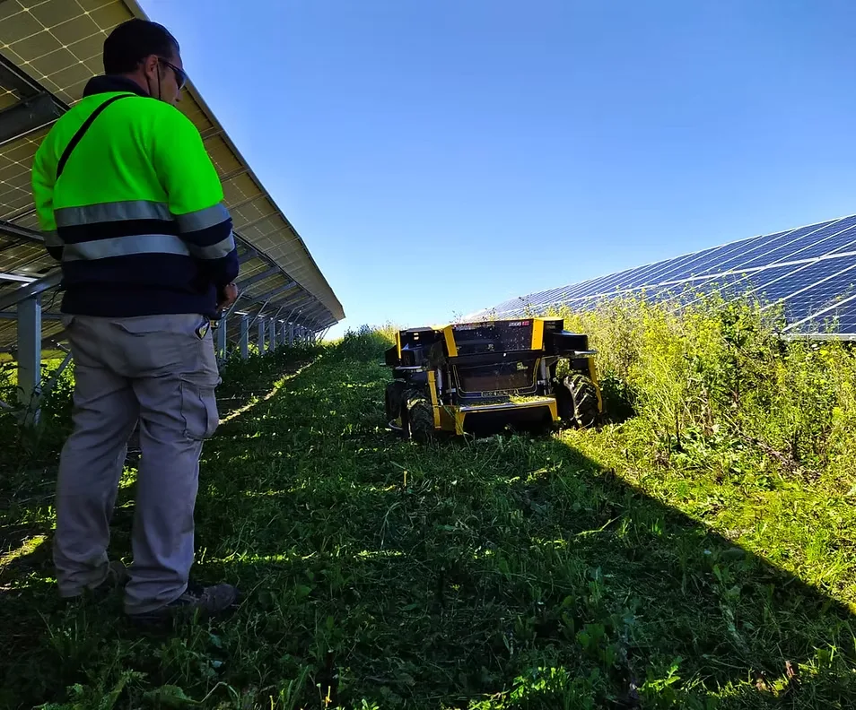 Operador controlando robot Spider entre paneles solares